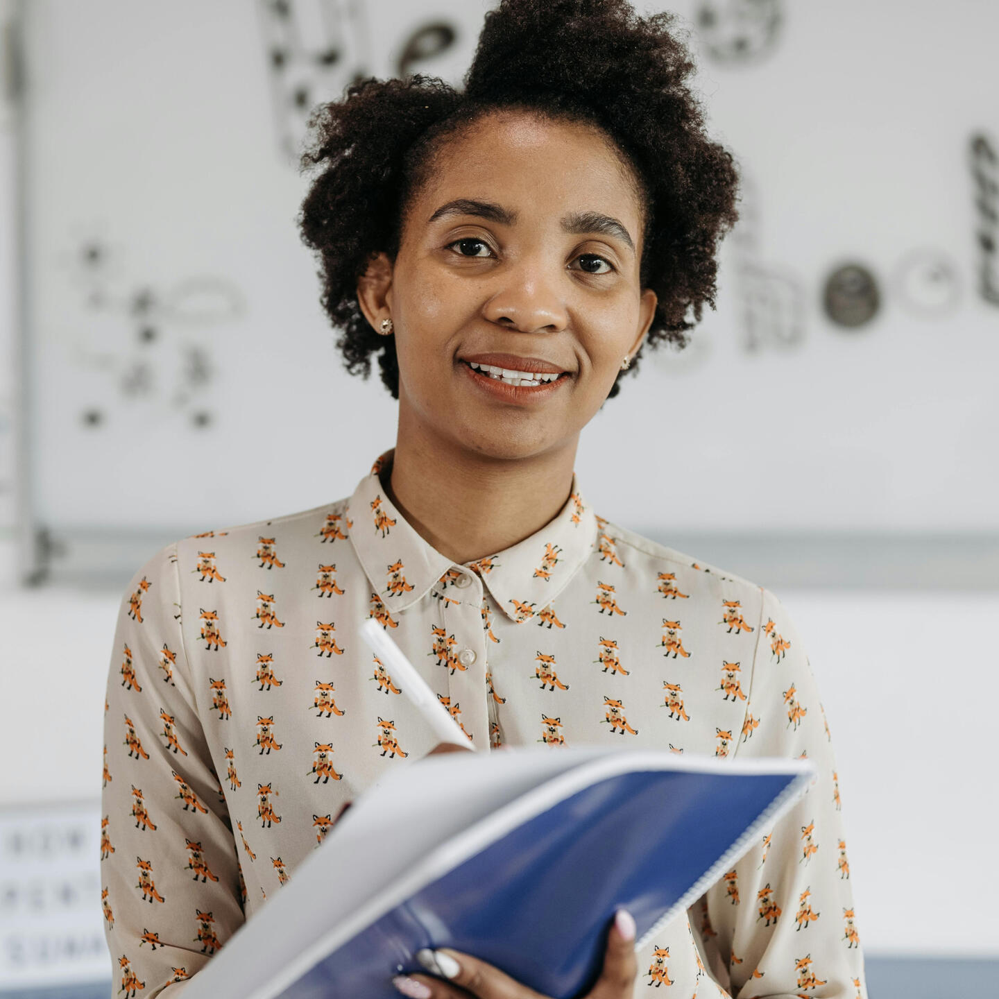 Peel Back Education Teacher A smiling teacher writing in a notebook.